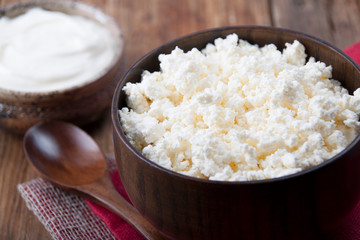 Home cottage cheese in a wooden bowl and sour cream