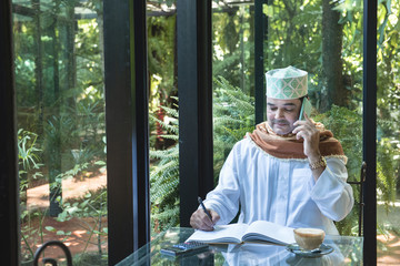 Arab muslim businessman use smartphone communication and write on book in coffee shop ,freelance no working space lifestyle.