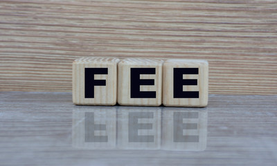 concept word fee on cubes on a beautiful wooden background with a mirror image
