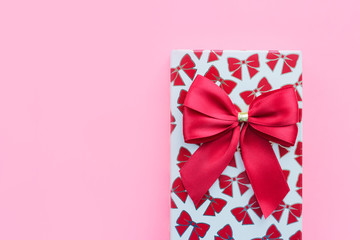 box with a red bow as a gift for the holiday on a pink background. Concept of attention signs and gifts.