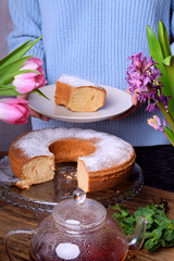 Piece of sponge cake on a white plate in female hands