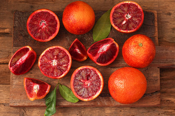 Sliced and whole ripe juicy Sicilian blood oranges on wooden background