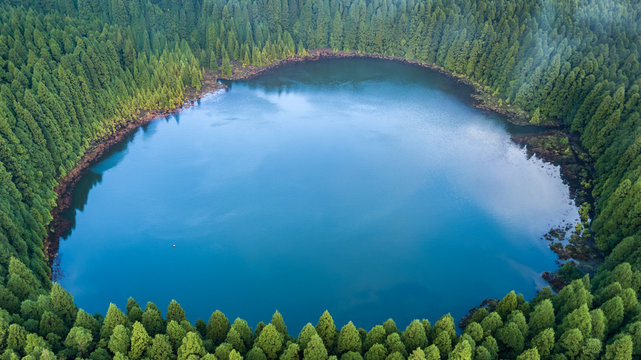 Drone aerial view of "Lagoa do Canario" lagoon surrounded by green forest located on Sao Miguel, Azores, Portugal.