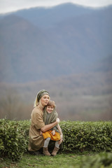 Naklejka na ściany i meble A woman with a child walking on a tea plantation.