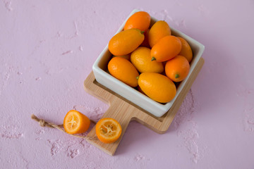 Kumquat in a cup on a pink background, sour fruit