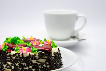 White Chocolate Cake. Beautifully decorate the cake in red, pink and green colors with flowers and hearts. It is arranged in a white plate, looks simple and the back is then white coffee.