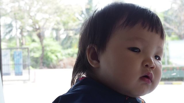 Cute asian infant baby girl Looking for or waiting dad or mom or parent.
