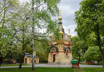 Chapel and tomb in Gomel park. Spring. Many tulips in the Gomel park. The facade of the chapel is made of carved stone and art metal, red unglazed terracotta and multicolor majolica, smalt mosaic.