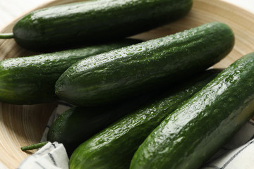 Bowl with cucumbers and towel on wooden background, close up