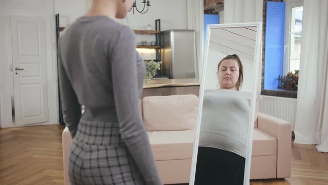 Slim girl looking at fat reflection in mirror. Eating disorder concept, body dysmorphia