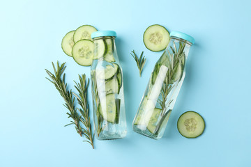 Bottles with infused cucumber water on blue background, top view