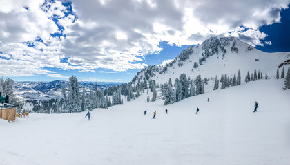 Winter mountain landscape of Snowbasin ski resort with skiers on the slopes.