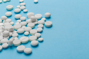 scattered white pills on a blue table. Layout for special offers such as advertising or other ideas. The concept of medicine, pharmacy and healthcare. Space for copy. flat lay for text or logo.