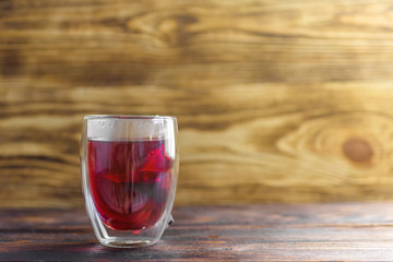 glass Cup with red fragrant tea brewed in a bag on a wooden background copy space. red useful tea for colds and flu