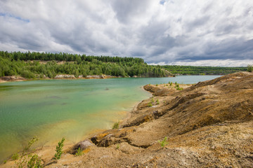 Fototapeta na wymiar Flooded clay quarry lake with green water landscape