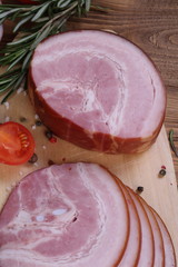 Pieces of sausage and ham on a wooden background