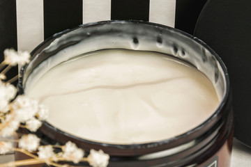 Hair mask, balm or conditioner in a wide round jar. Glossy texture of a nourishing moisturizing cosmetic product, close up, selective focus