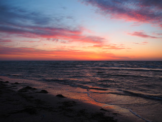 Fototapeta premium The waves push the algae onto the sandy beach at sunrise