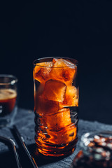 Cubes of frozen coffee in a tall glass on a black table, the process of making iced coffee