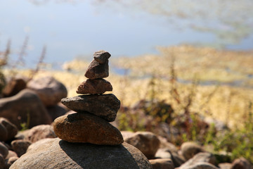 Fototapeta na wymiar Stacks of natural rocks by the beach of lake Valkeinen in Kuopio, Finland. Beautiful inspiring zen like view to a garden with rocks by the water. Relaxing, simple view, perfectly peaceful and idyllic.
