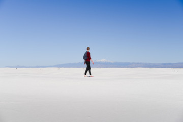 A man walking across sand dunes. 