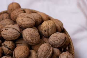 Walnuts on a white background in a small wicker basket