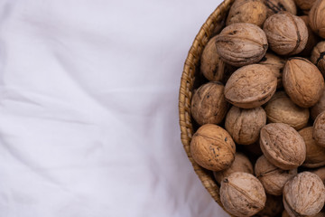 Walnuts on a white background in a small wicker basket