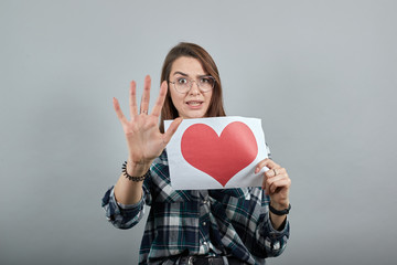 Young brunette girl blue green in checked shirt on grey background a dissenting woman in glasses...