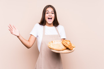 Young caucasian baker woman isolated receiving a pleasant surprise, excited and raising hands.