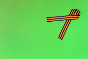Ribbon of St. George on a green background for Victory Day. May 9, 2020 - 75 years of Victory in the Great Patriotic War. Flat lay, copy space, top view.