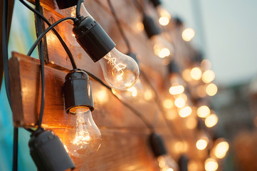 Glowing light bulb on a wooden background with bright bokeh.