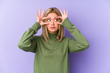 Young blonde caucasian woman isolated keeping eyes opened to find a success opportunity.