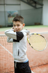 Boy with a tennis racket on an indoor tennis court