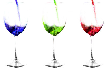 Three glasses with colored liquids. Blue, green and red. The fluid flows into the glasses
