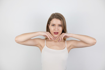 Fototapeta premium young beautiful blond woman looks happy satisfied with her skin touching her face standing on isolated white background, healthcare and beauty concept