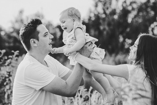 Portrait of a mom, dad and girl playing in the park. Concept of happy family. Black and white photo.