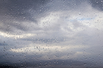water drops on glass and cloudy gray sky on background