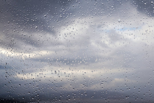 water drops on glass and cloudy gray sky on background