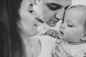 Portrait of a happy young family spending time together on nature. Mom, dad holds daughter stand in the park. The concept of family holiday. Black and white photo.