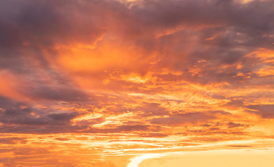 Orange black sky with scattered clouds during sunset
