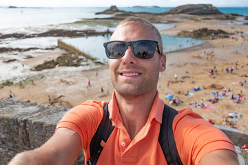 Portrait beau gosse charmant jeune homme caucasian blond aux yeux bleu joyeux et confiance en soi séduisant chanceux charismatique européen heureux zen abbaye mont saint michel normandie