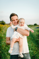 Fototapeta premium The Daughter hugging father on nature on summer day vacation. Dad and girl playing in the park. Concept of happy family. Closeup.