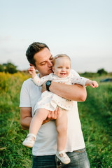 The Daughter hugging father on nature on summer day vacation. Dad and girl playing in the park. Concept of happy family. Closeup.