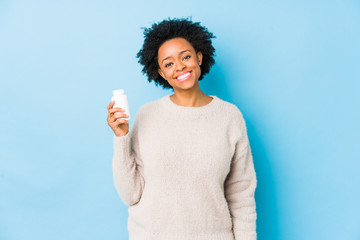 Middle age african american woman holding a vitamin bottle happy, smiling and cheerful.