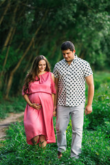 Future parents walking in the park. pregnant woman in pink dress