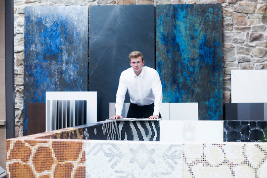 Portrait of a Salesman standing in a tile showroom surrounded by various different tile samples