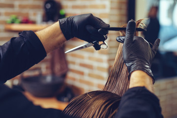 Close-up of man haircut, master does the hair styling in barber shop.