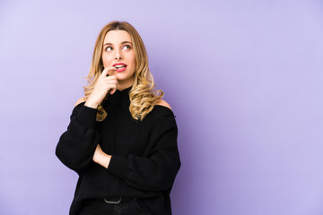 Young blonde woman isolated relaxed thinking about something looking at a copy space.