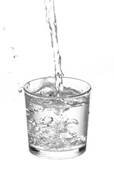 Water flowing into glass isolated on white background