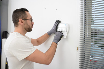 handsome man worker installing alarm technology insurance in home for burglar prevention - obrazy, fototapety, plakaty